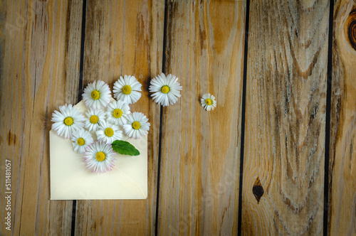 Envelope with vintage style daisies on wooden boards  top view  selective focus with copy space. natural light