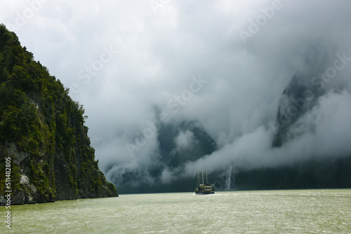 A ship sailing in the mist through Milford Sound, New Zealand