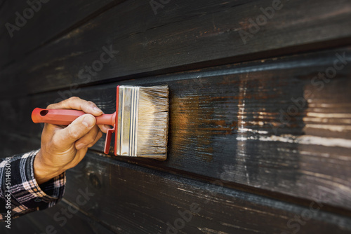 Foto hand with brush restore paint of old wooden house exterior wall