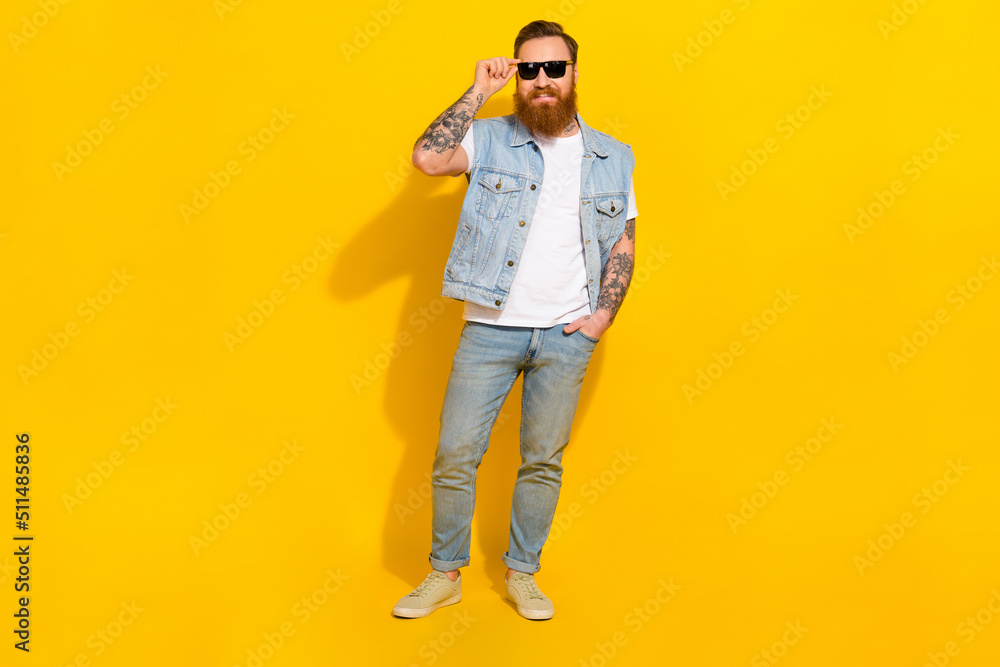 Photo of pretty cool man wear jeans waistcoat arm dark eyewear walking isolated yellow color background Photo of pretty cool man wear jeans waistcoat arm dark eyewear walking isolated yellow color background