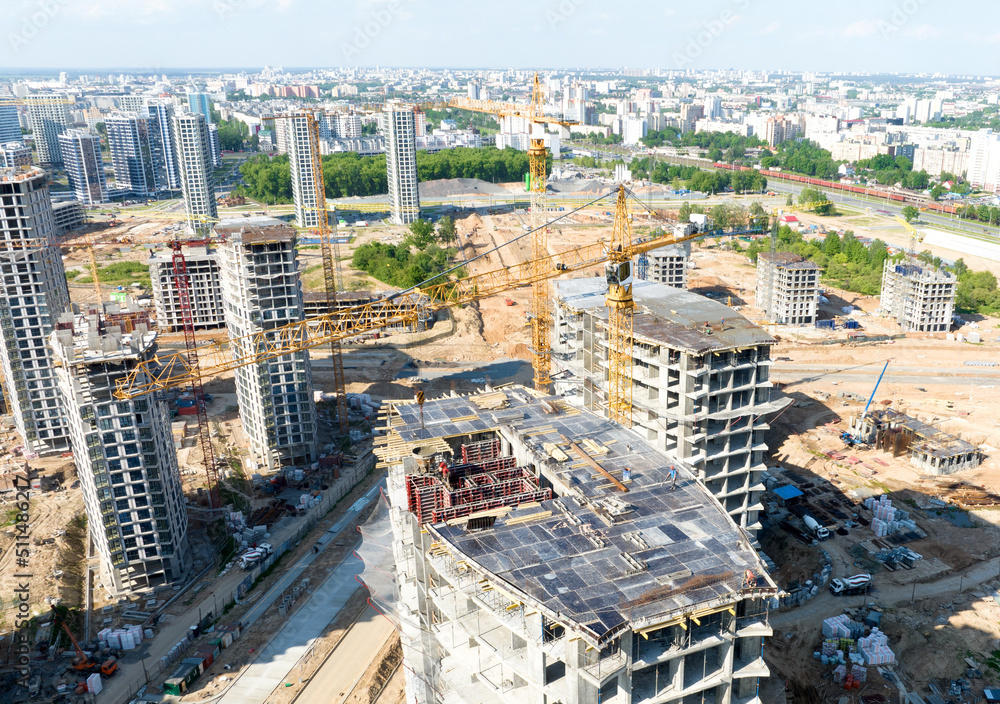 Fototapeta premium Сonstruction site with tower cranes on building construction. Builder on formworks. Cranes on pouring concrete in formwork. Tower cranes on construction in built environment. Buildings renovation..