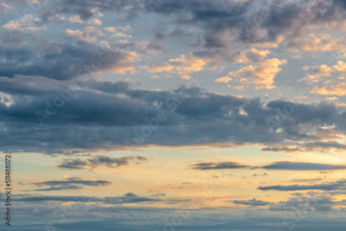 Soft deep orange sky, illuminated clouds at bloody sunset as a background.