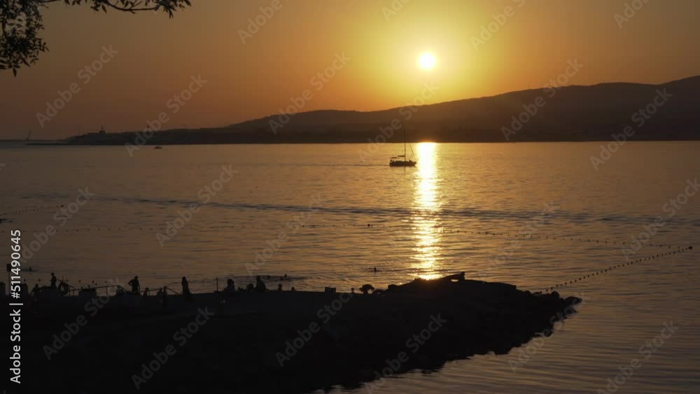 Sunset on Black Sea coast. Boat floats on sea surface of water in reflection of setting sun sunlight. Tranquil background of idyllic resort holiday. Sunset on Black Sea coast. Boat floats on sea surface of water in reflection of setting sun sunlight. Tranquil background of idyllic resort holiday.