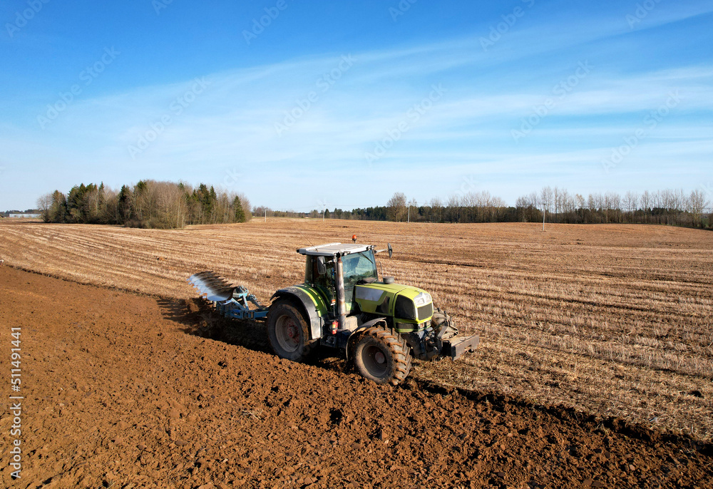 Obraz premium Tractor plowing field. Tractor plow soil cultivating. Cultivated land and soil tillage. Agricultural tractor on farm field cultivation. Tractor disk harrow plowing farm field. Agronomy and agrarian..