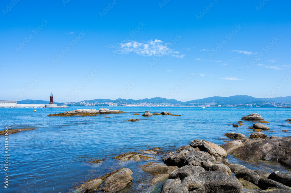 Rock beach in the Vigo estuary with the lighthouse and copy space.