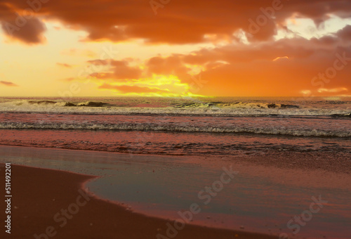 Waves in sea on sunset background. Waves in sea during storm and wind. Wave from the sea goes on land to the beach. Splashing Waves in ocean  background  texture. Wave at Rising Storm. Seashore.