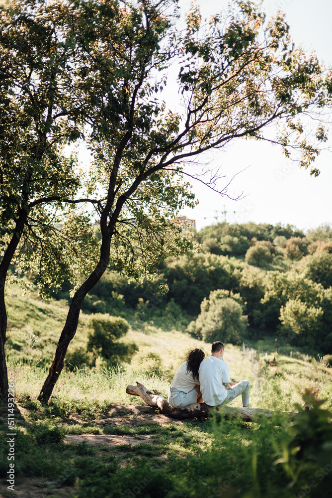 Young family - couple during an outdoor walk, sitting on the lawn, enjoying the nature