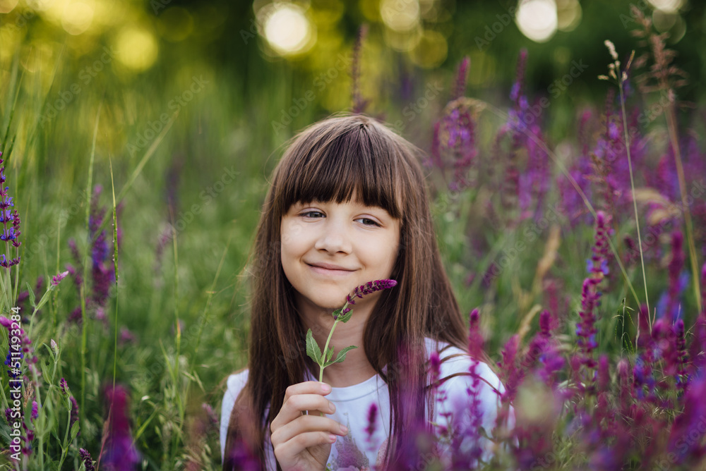 Cute happy girl 7-8 years old, sitting in the lavender field, smiling Cute happy girl 7-8 years old, sitting in the lavender field, smiling