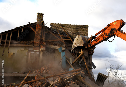 Demolition the house in the rural. Excavator bucket destruction old home on construction site. Backhoe demolishes building. Tearing Down a Houses. Destroy concrete for recycling and reuse.