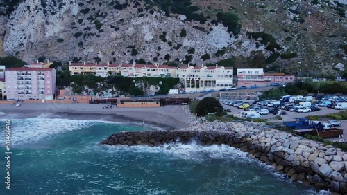 Turquoise Beach With Crashing Waves Onto Sea Walls On Catalan Bay In Gibraltar. Aerial Pullback