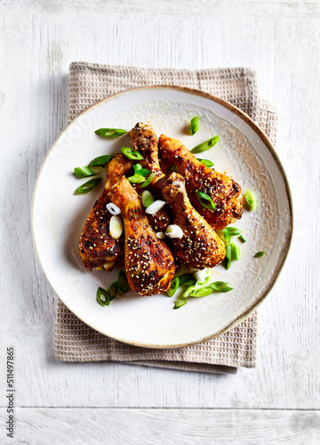 Roasted chicken legs with sesame seeds and spring onion on the plate