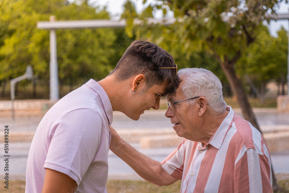 Joven frente con frente con un señor mayor, en el parque, con gesto cariñoso y sonrientes. Fotografía horizontal. Joven frente con frente con un señor mayor, en el parque, con gesto cariñoso y sonrientes. Fotografía horizontal.