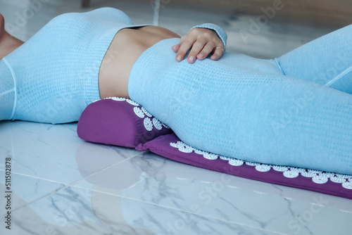 Acupressure mat massage therapy. Close-up young woman lying on orthopedic acupressure mat for self health massage in living room at home indoors. photo