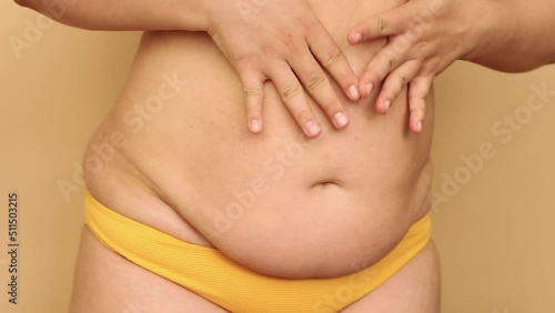 Wallpaper Mural Close-up of unrecognizable plump woman wearing yellow bra, bikini, showing saggy stomach, dancing, moving hands, caressing body on beige background. Body positive, weight loss, having fun, obesity. Torontodigital.ca