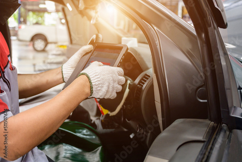 The mechanic works at the car service center. Use the scanner to diagnose vehicle problems using an electronic OBD and OBD2 device on your tablet. photo