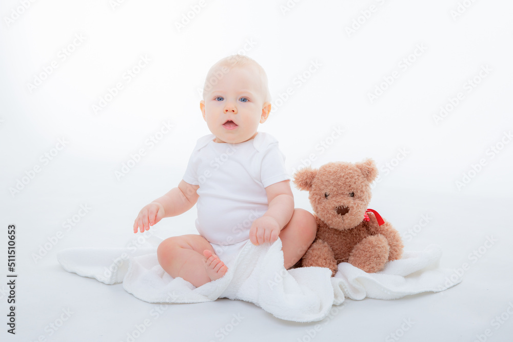 baby boy in a white bodysuit sits with a teddy bear on a white background baby boy in a white bodysuit sits with a teddy bear on a white background