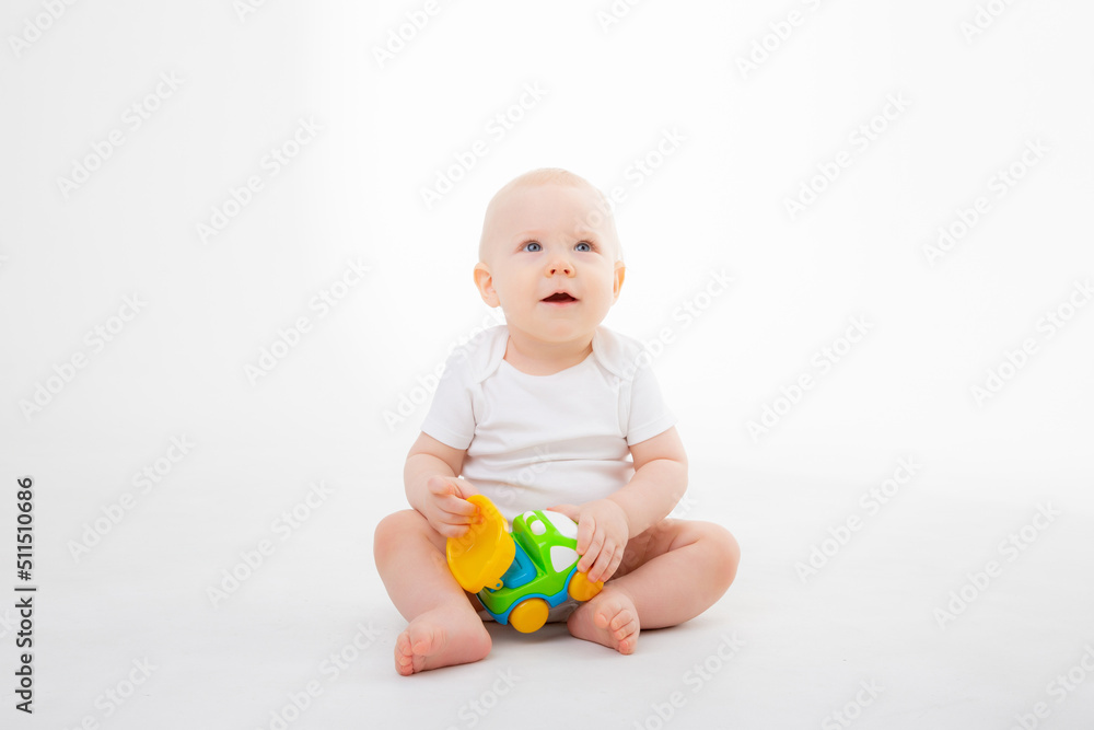 a baby boy in a white bodysuit is sitting playing with a typewriter smiling on a white background a baby boy in a white bodysuit is sitting playing with a typewriter smiling on a white background