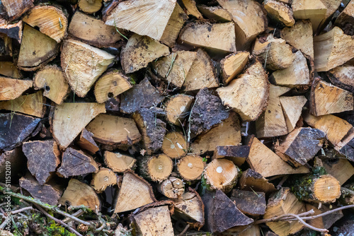 stacked split firewood, from small, thin tree branches, with cut grass on the tree, light and dark in color