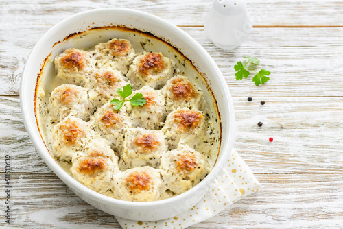 Sour cream turkey meatballs in baking dish on wooden background. Top view, copy space, flat lay.