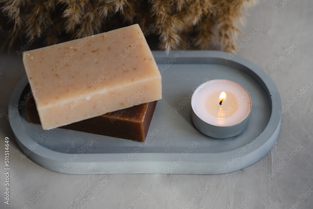 Handmade natural soap and plate. The candle is burning.