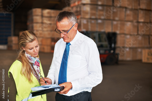 Your copyspace will fit in here perfectly. Two colleagues talking to one another in a warehouse filled with cardboard boxes.