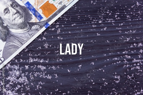LADY - word (text) on a dark wooden background, money, dollars and snow. Business concept (copy space).