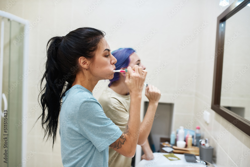 Side view of girls brush teeth with toothbrushes Side view of girls brush teeth with toothbrushes