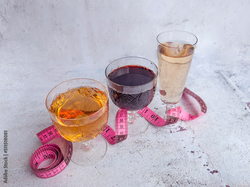 Glasses of wine and rose with  measuring tape. Calories in alcohol are extra-fattening 