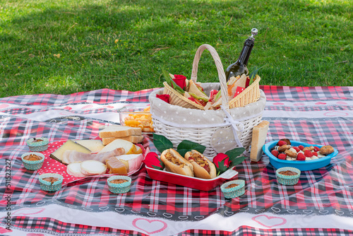 Fototapeta Naklejka Na Ścianę i Meble -  tablecloth with basket and picnic food on the lawn outdoors