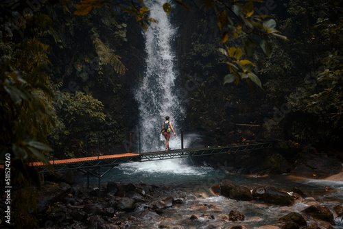 Woman on a bridge admiring a waterfall in front