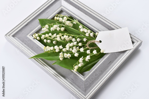 Gray frame and bunch of liles of the valley on white background photo