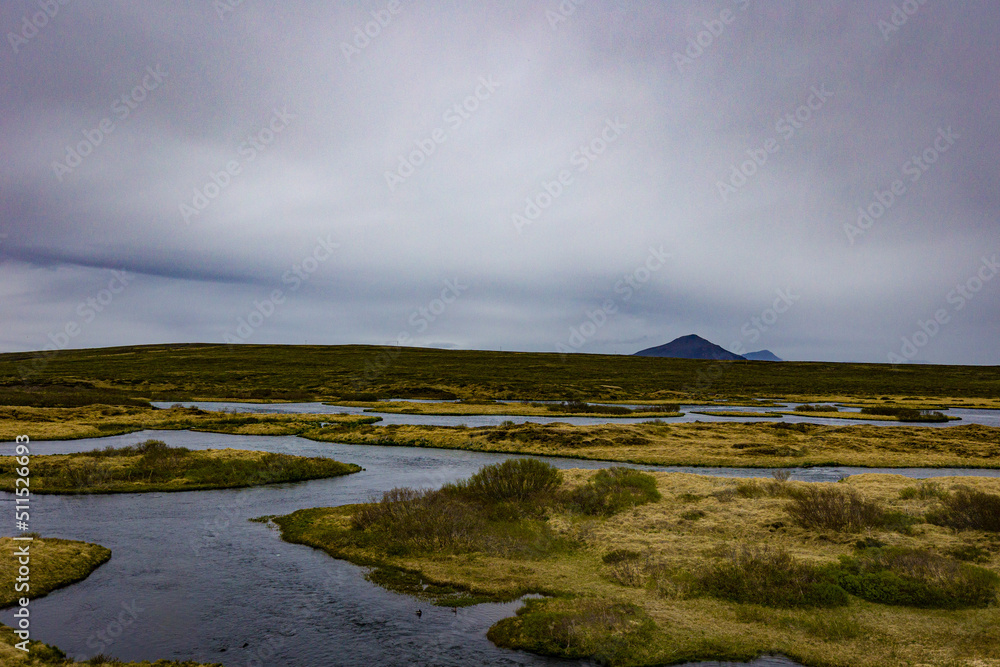 Icelandic valley with flowing river. Mountain range on the horizon.