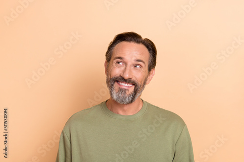 Portrait of satisfied minded man toothy smile look interested empty space isolated on beige color background