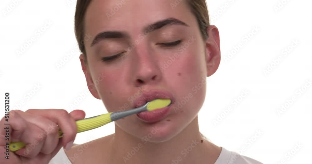Portrait of a white woman brushing her teeth in the morning without toothpaste and with a green toothbrush. Isolated on white background. Portrait of a white woman brushing her teeth in the morning without toothpaste and with a green toothbrush. Isolated on white background.