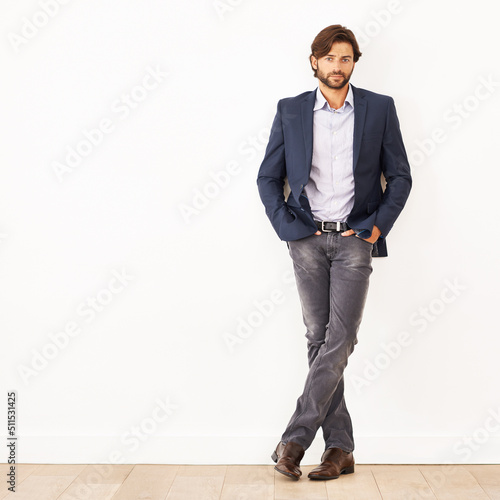 His confidence knows no bounds. Portrait of a confident young businessman leaning against a white wall.