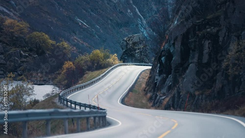 Two-lane country road winds between the steep rocky slopes. Slow-motion, pan forward. photo