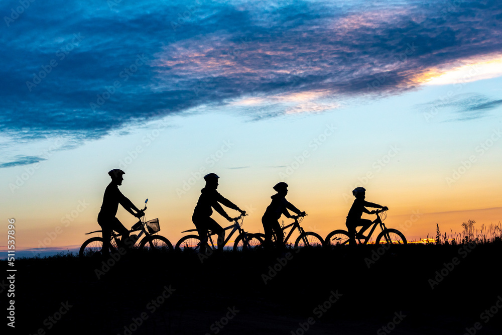 parents and kids ride bicycle at sunset. family on cycle ride in countryside. Silhouette of cyclist parents and kids ride bicycle at sunset. family on cycle ride in countryside. Silhouette of cyclist