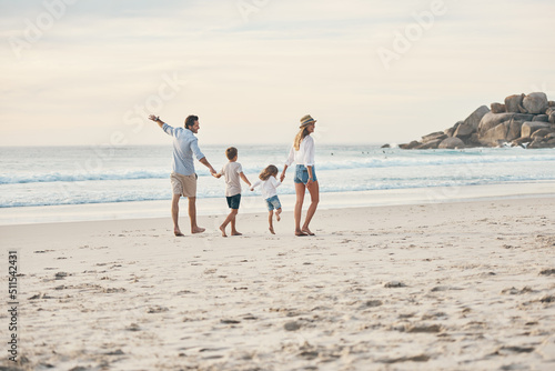 Todays little moments become tomorrows memories. Full length shot of a happy couple holding hands with their two children and walking along the beach.
