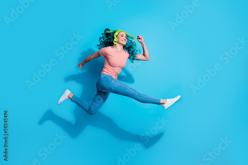 Fototapeta Naklejka Na Ścianę i Meble -  Full size profile side photo of energetic active girl running in air look empty space isolated on blue color background