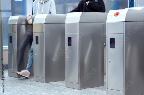 People passing turnstiles, closeup view. Fare collection system