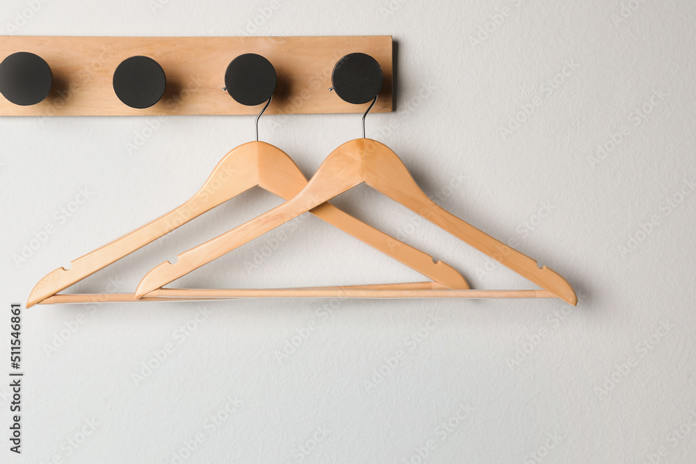 Rack with empty wooden clothes hangers on white wall - obrazy, fototapety, plakaty 