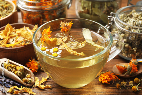 Fotobehang Freshly brewed tea and dried herbs on wooden table, closeup