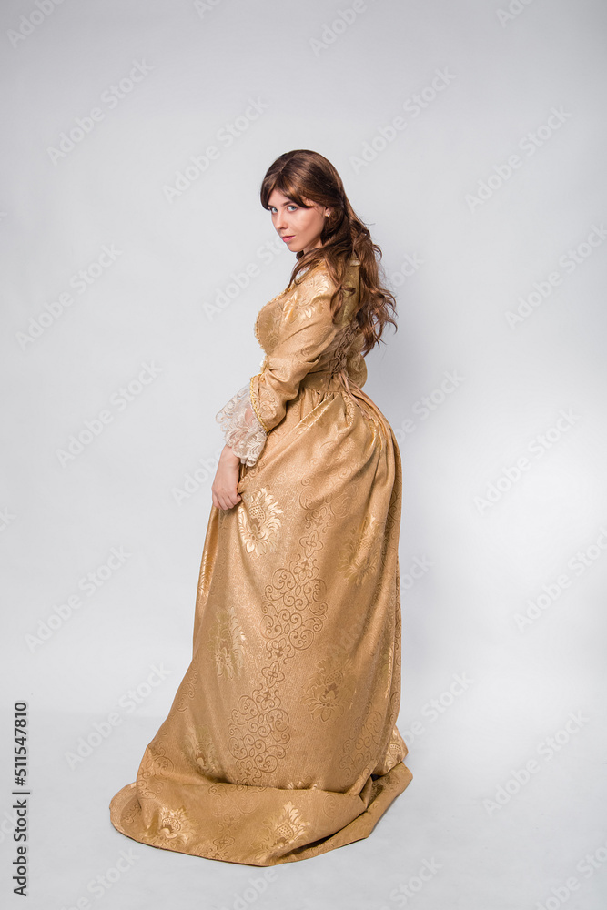Full length portrait of a woman in a gold dress in the style of the rococo era, standing with her back forward and posing isolated on a white background. Full length portrait of a woman in a gold dress in the style of the rococo era, standing with her back forward and posing isolated on a white background.