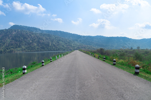 The country road in front with mountains on the forest side and rivers conveys success or journey or the beginning of something with sky and clouds.