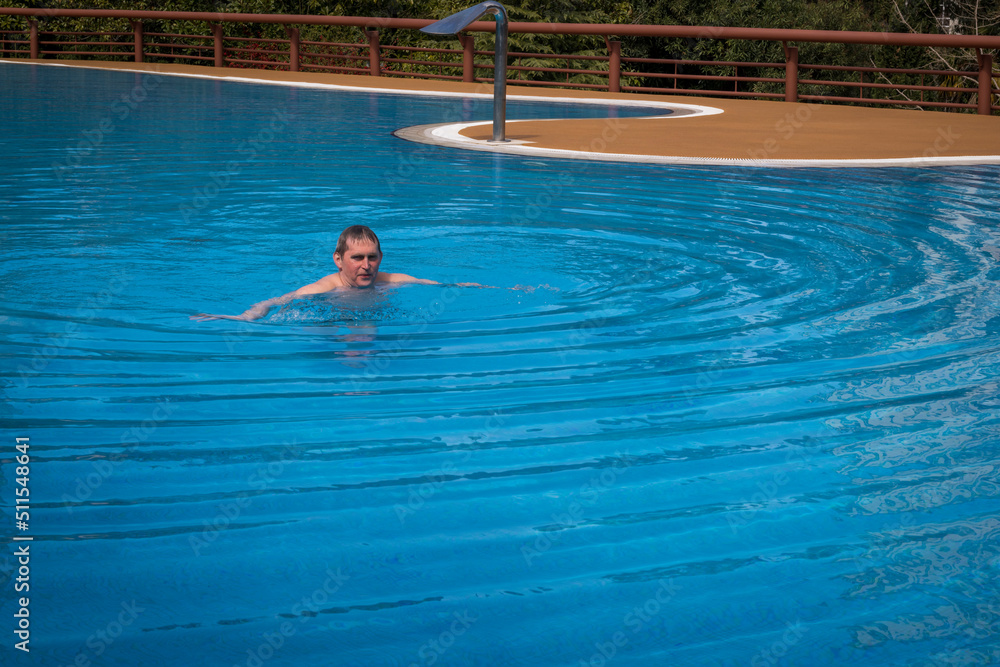 An elderly gray-haired retired man swims in the pool. The concept of a healthy active lifestyle in old age