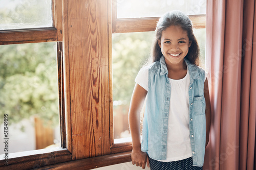 Happy kids make happy homes. Portrait of a happy young girl standing next to a window at home. photo