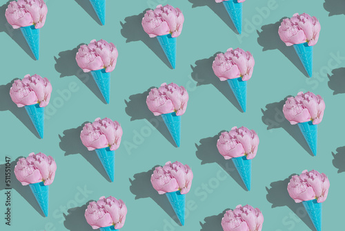 Creative blue toy ice cream cone with pink peony fluffy flower on blue minimal background with copy space flat lay. Botany idea for summer or spring wallpaper or greeting card. Seamless pattern.