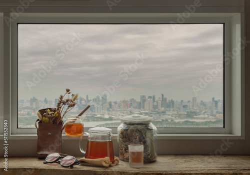 Refreshing with Chinese herbal tea (Jub Lieng) served with honey on old wooden table with city view. Herbal plant and healthy drinks concept, Selective focus. photo