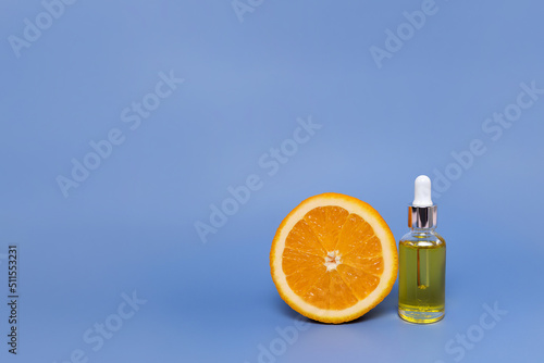 Cosmetic bottle with vitamin C serum and half an orange