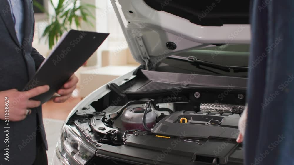 car sales business, male manager shows a new engine to a client in a auto center, close-up car sales business, male manager shows a new engine to a client in a auto center, close-up